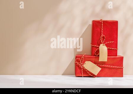 Weihnachtsschablone mit Geschenkboxen auf einem Tisch mit Schatten und Sonnenstrahlen, die sanft an die Wand fallen und eine festliche Winteratmosphäre schaffen Stockfoto