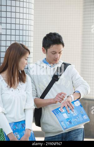 College-Paar, das sich auf dem Campus eine tragbare Uhr ansieht Stockfoto