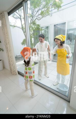 Paare mittleren Alters und Enkel putzen Fenster Stockfoto