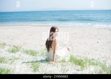 Frau, die am Sandstrand sitzt Stockfoto