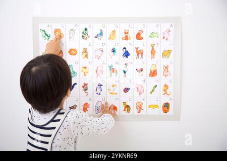 Junge, der auf die Aiueo-Karte zeigt Stockfoto