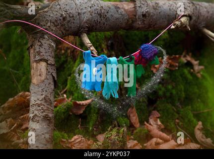 Eine skurrile Szene mit winzigen, farbenfrohen Kleidungsstücken, die an einer Wäscheleine im Wald hängen und jetzt mit magischem Staub um sie herum schwebt. Der Mini Stockfoto