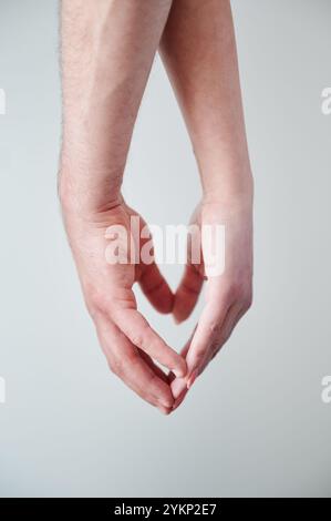 Nahaufnahme der Hände von Mann und Frau, die Herzsymbol für Hand machen. Ein Paar hält Hände auf weißem Hintergrund. Konzept von Liebe, Intimität, Unterstützung und Vertrauen. Stockfoto