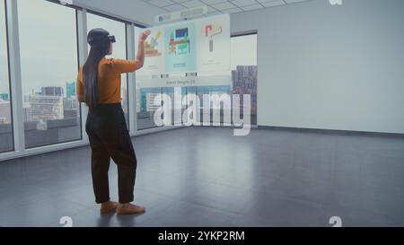 Die talentierte asiatische Designerin in Augmented-Reality-Headsets nutzt Virtual Interior Design Software, um stilvolle Wohnungen oder Büroräume mit 3D-Möbeln und -Ausstattung zu arrangieren. Futuristische VFX-Animation. Stockfoto