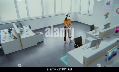 Kreative asiatische Designerin, die ein Augmented-Reality-Headset trägt, nutzt Virtual Interior Design Software und Controller, um einen Büroraum mit 3D-Möbeln und -Geräten zu bauen. Futuristische VFX-Animation. Stockfoto