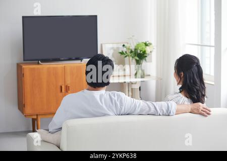 Rückansicht eines Paares, das sich beim Fernsehen im Wohnzimmer erholt Stockfoto