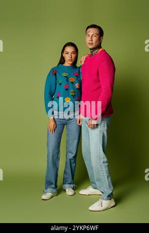 Ein stilvolles junges Duo zeigt seine einzigartige Mode mit auffälligen Pullis und lässigen Jeans. Stockfoto