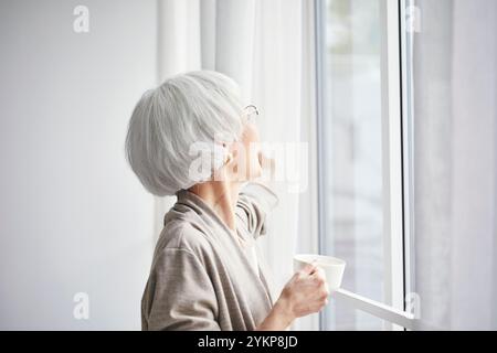 Seniorin öffnet Vorhänge Stockfoto