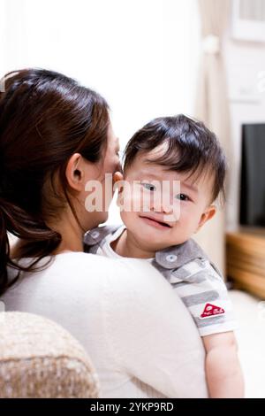 Mutter hält und beruhigt ein weinendes Baby im Wohnzimmer Stockfoto