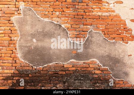 Nahaufnahme einer alten Ziegelmauer mit teilweise abblätterndem Putz, die rote Ziegelsteine freilegt und rustikalen und Vintage-Charme verleiht. Stockfoto