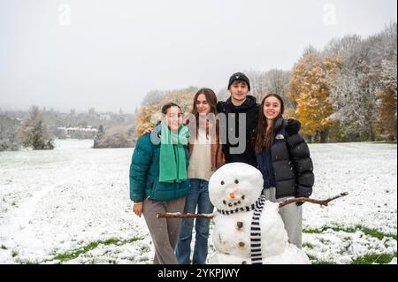 Oxford Brookes Studenten, (l-r) Abie, Jade, Cole und Felicity erwachten von der Überraschung eines frühen Schneefalls im November. Sie machten sich auf den Weg zum South Park, der die berühmten Türme von Oxford überblickt, um im Schnee zu spielen. Zusammen bauten sie einen Schneemann, fügten Stöcke für Arme, Steine für Augen und Knöpfe hinzu, eine Karottennase und natürlich einen Schal, um ihre Kreation warm zu halten. Stockfoto