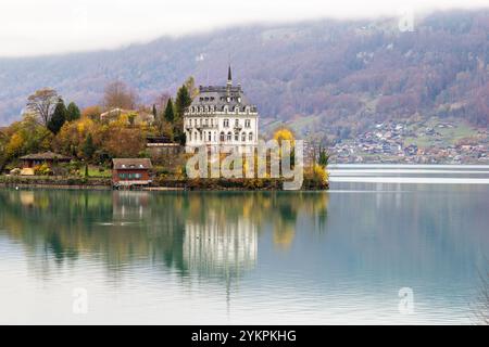 iseltwald, Schweiz - 06. November 2020: Schloss Seeburg am Iseltwald im türkisfarbenen Brienzersee an einem herbstlich bewölkten grauen Tag, Schweiz. Stockfoto