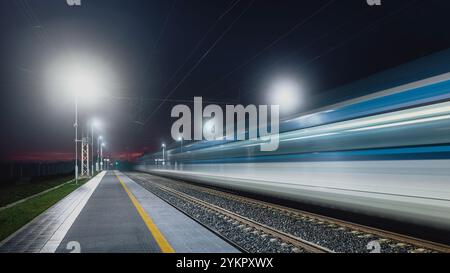 Moderne Eisenbahn bei Nacht. Leichte Spur eines Hochgeschwindigkeitszuges im Bahnhof. Der moderne Intercity-Personenzug. Stockfoto