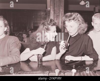 Vintage-Foto vom Leben amerikanischer Bergleute. Ella Jane Fain (rechts), Tochter von Harry Fain, Bergmann, und ihrer Cousine, haben vor der Filmvorführung eine Cola in einem Limonadenbrunnen. Inland Steel Company, Wheelwright Nr. 1 & 2 Mines. Wheelwright, Floyd County, Kentucky. USA. 1946 Stockfoto