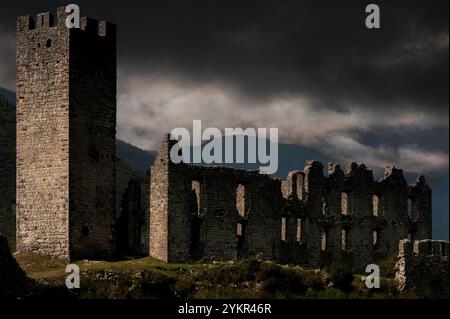 Unter stürmischem Himmel erhebt sich ein mittelalterlicher Wachturm von 1311 über den Ruinen von Castel Belfort bei Spormaggiore, Trentino-Südtirol, Italien. Der Wachturm und die Burg wurden ursprünglich gebaut, um den Eingang zum Val de Non und zu den Brenta-Dolomiten zu bewachen. Die Burg wurde nach einem verheerenden Brand 1670 wieder aufgebaut und Ende der 1700er Jahre aufgegeben Stockfoto