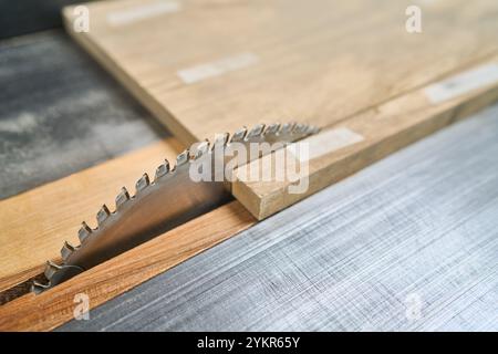 Detaillierte Ansicht eines Kreissägeblattes beim Schneiden durch ein Holzbrett, wodurch Präzision und Handwerkskunst in der Holzbearbeitung hervorgehoben werden. Ideal für Handwerkskunst Stockfoto