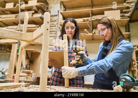 Zwei Frauen in einem Holzhof arbeiten im Rahmen einer Ausbildung und Lehre. Sie konzentrieren sich auf Teamarbeit und Kompetenzaufbau mit einem praktischen ca. Stockfoto
