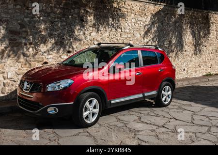 Stilvolles Auto Neues 4-türiges Auto. Modernes rotes Familienauto. Rotes Auto parkte an einem sonnigen Tag auf der leeren Straße. Subkompakter Crossover-SUV-Modelltyp, Seitenansicht Stockfoto