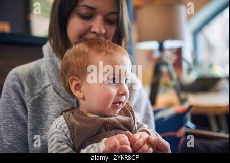 Mutter und Baby verbringen einen fröhlichen Moment in gemütlicher Innenumgebung an einem sonnigen Nachmittag Stockfoto