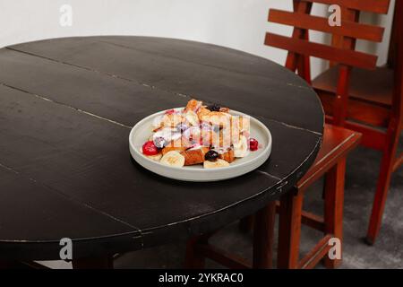 Französischer Toast mit Erdbeere, Heidelbeere, gemischten Beeren, Honig, Eis, und Banane serviert auf Teller am Tisch im Restaurant im Freien. Süße Leckereien von Fran Stockfoto