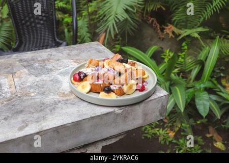 Französischer Toast mit Erdbeere, Heidelbeere, gemischten Beeren, Honig, Eis, und Banane serviert auf Teller am Tisch im Restaurant im Freien. Süße Leckereien von Fran Stockfoto