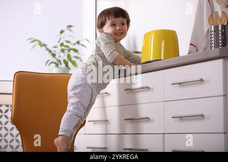 Kleiner Junge, der mit Toaster in der Küche spielt. Gefährliche Situation Stockfoto