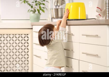 Kleiner Junge, der mit Toaster in der Küche spielt. Gefährliche Situation Stockfoto