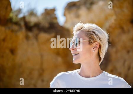 Kaukasische Frau mit Zahnspangen, die mit verschwommenem Hintergrund zur Seite schaut, in São Rafael's Beach, Albufeira, Algarve - Portugal Stockfoto