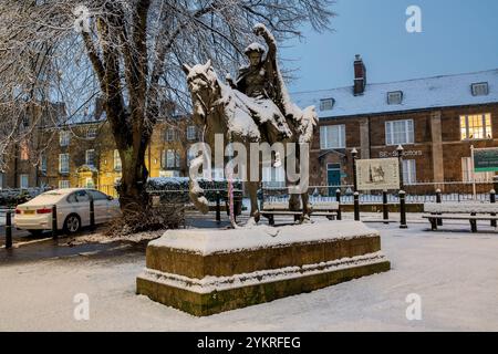 Schöne Dame Bronzestatue / Skulptur auf einem walisischen Spindelpferd neben Banbury Cross im Schnee bei Sonnenaufgang. Banbury, Oxfordshire, England Stockfoto