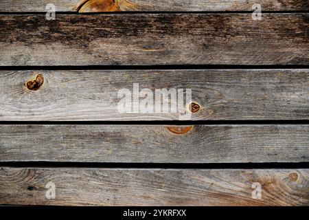 Nahaufnahme verwitterter Holzdielen mit natürlicher Holzmaserung und Knoten. Rustikale, strukturierte Oberfläche in Erdtönen, ideal für Hintergründe. Stockfoto