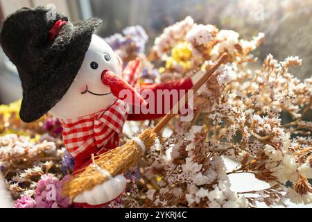 Farbenfrohe Aufnahme eines getrockneten Blumenstraußes lila limonium sinuatum mit einer Schneemannfigur, weicher Fokus Stockfoto