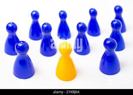 Ein gelber Bauer in einer Menge blauer Bauer isoliert auf weißem Hintergrund, weicher Fokus Stockfoto