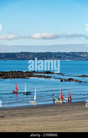 Yachten mit roten und weißen Segeln starten an einem sonnigen Herbstmorgen in Cornwall England, Großbritannien, vom Strand in Marazion Stockfoto