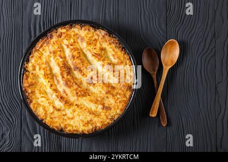 Veganer Hirtenkuchen in Backform auf schwarzem Holztisch, horizontaler Blick von oben, flacher Lagenplatz, freier Platz Stockfoto