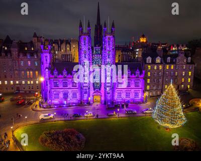 Aus der Vogelperspektive von der Drohne des New College an der Edinburgh University, beleuchtet in lila mit traditionellem Weihnachtsbaum auf dem Hügel, Edinburgh, Schottland Stockfoto