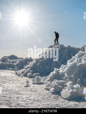 Menschen klettern auf riesigen Eishaufen, die jedes Frühjahr an das Seeufer geschoben werden, während das Eis des Sees vom langen, harten Winter abschmilzt. Stockfoto