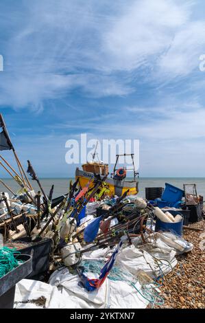 Kleines gelbes Fischerboot (Clara) hinter Anhäufungen von Angelschrott am Strand von Hastings Stockfoto