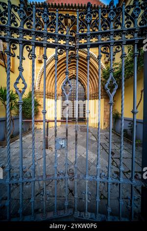 Das komplizierte Eisentor vor der Mudéjar-Fassade der Kirche San Juan de la Palma in Sevilla, Spanien, hebt historische Architektur und Kultur hervor Stockfoto