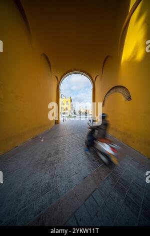 Ein Motorradfahrer fährt unter dem Arco de la Macarena im historischen Sevilla, Spanien. Stockfoto