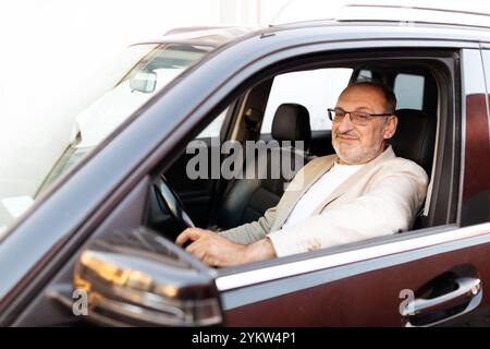 Reifer Mann, der tagsüber eine gemütliche Fahrt in einem modernen Auto genießt Stockfoto