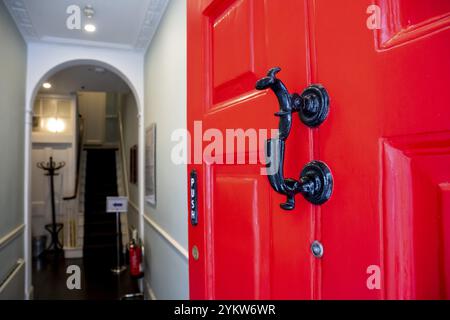 Offene rote Tür mit schwarzem Türklopfer, Eingang zum Charles Dickens Museum, 48-49 Doughty Street, Holborn, London Borough of Camden, England, Great Stockfoto