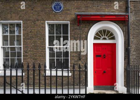 Rote Eingangstür in einem Backsteingebäude mit gusseisernem Zaun, Charles Dickens Museum, 48-49 Doughty Street, Holborn, London Borough of Camden, England Stockfoto