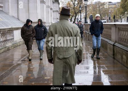 In Whitehall geht ein zicil Diener an jungen britischen Bauern vorbei, die gegen die Erbschaftspläne der Labour-Regierung protestieren, London, England, Großbritannien Stockfoto