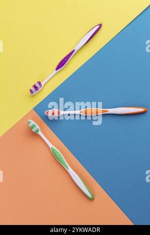 Vertikale Aufnahme Draufsicht drei bunte Zahnbürsten. Lebendiger, mehrfarbiger Hintergrund Stockfoto
