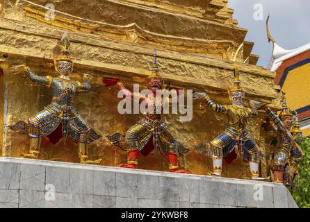 Ein Bild von Statuen am Fuße eines goldenen Chedi im Großen Palast in Bangkok Stockfoto