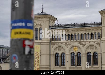 Ein Bild des Friedensnobelzentrums und ein verschwommener Aufkleber Hände weg von der Ukraine im Vordergrund Stockfoto