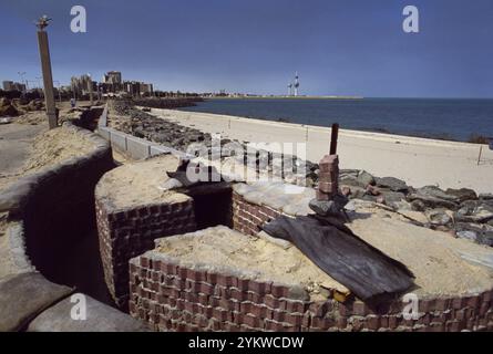 Erster Golfkrieg: 11. März 1991 die ikonischen Kuwait Towers stehen im Hintergrund hinter einem verlassenen Graben der irakischen Armee am Strand von Ali Baba in Kuwait City. In Erwartung der Invasion der Koalitionstruppen aus dem Meer, legten die Iraker Stacheldraht und Anti-Landungsboote entlang des Strandes und in die Untiefen. Auch die Strände wurden abgebaut. Stockfoto