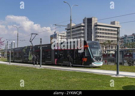 Ein Bild einer Straßenbahn in Izmir, die auf Straßen mit grünem Gras fährt Stockfoto