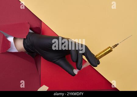 Schließen Sie die Handspritze mit gelbem Glitzer. Roter und gelber Papierhintergrund Stockfoto