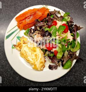 Nahaufnahme eines dekorierten Tellers mit Salat, bestehend aus verschiedenen Arten von roten und grünen Eichenblattsalaten, Lammsalat und Snacktomaten, Fisch Stockfoto